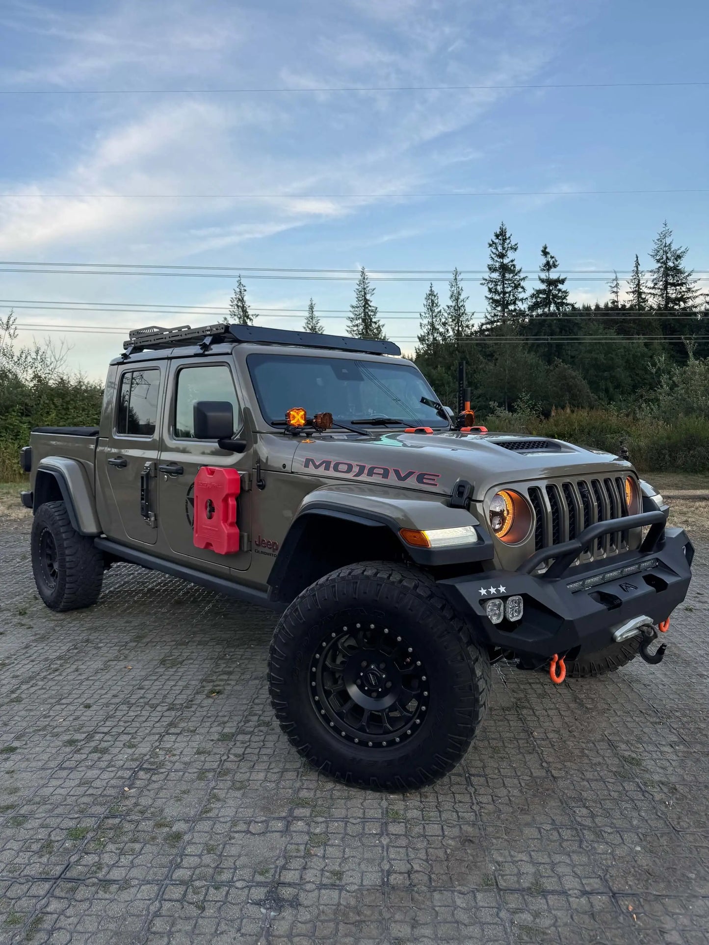 Jeep Mojave truck on a paved surface with trees in the background and roof rack