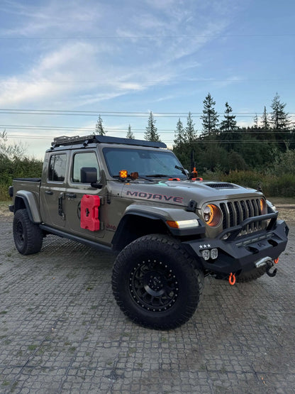 Jeep Mojave truck on a paved surface with trees in the background and roof rack